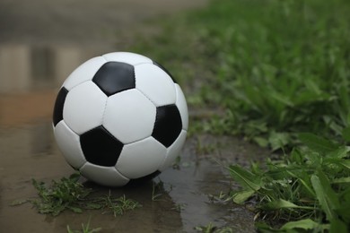 Photo of Soccer ball in puddle outdoors, space for text