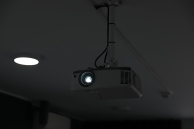 Modern video projector on ceiling in room