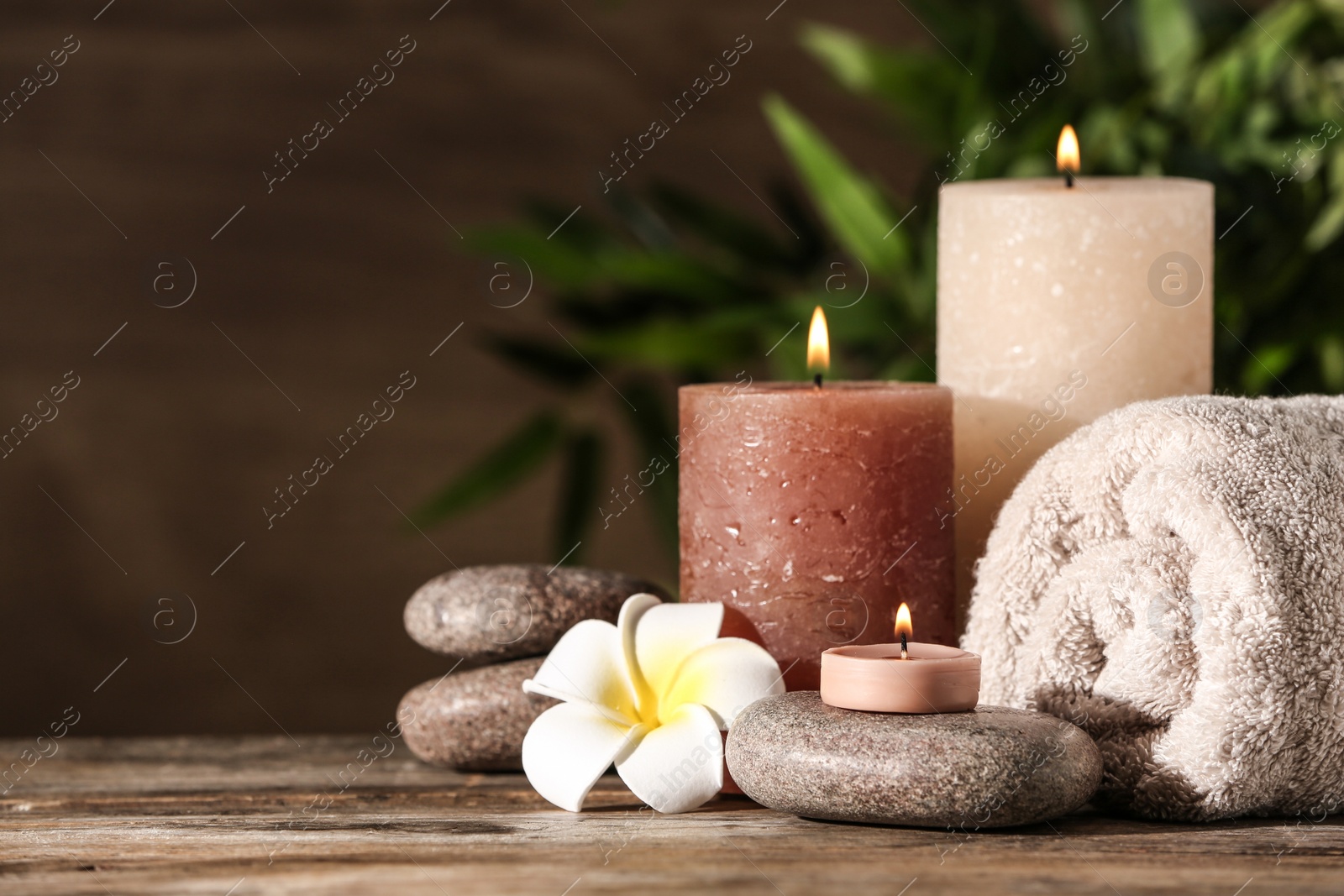 Photo of Composition with candles and spa stones on wooden table. Space for text