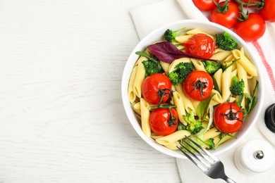 Photo of Bowl of delicious pasta with tomatoes, arugula and broccoli on white wooden table, flat lay. Space for text