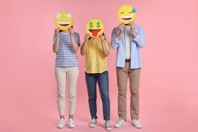 Photo of People covering faces with emoticons on pink background