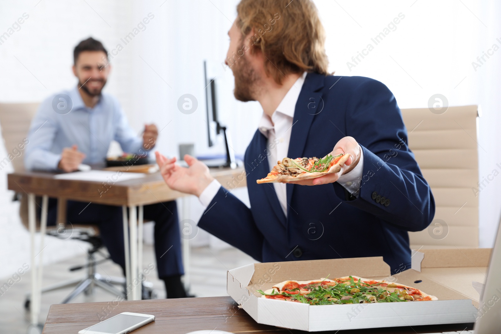 Photo of Office employees having lunch at workplace. Food delivery