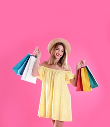 Beautiful young woman with shopping bags on color background