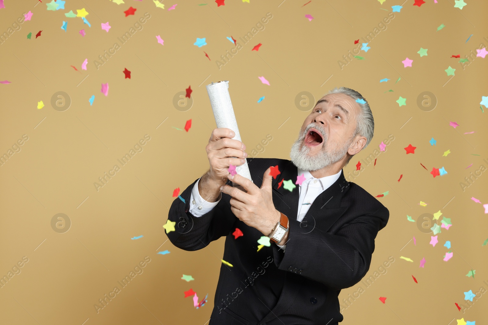 Photo of Emotional man blowing up party popper on beige background