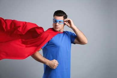 Photo of Man wearing superhero cape and mask on grey background