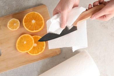 Photo of Woman wiping knife with paper towel at table, top view