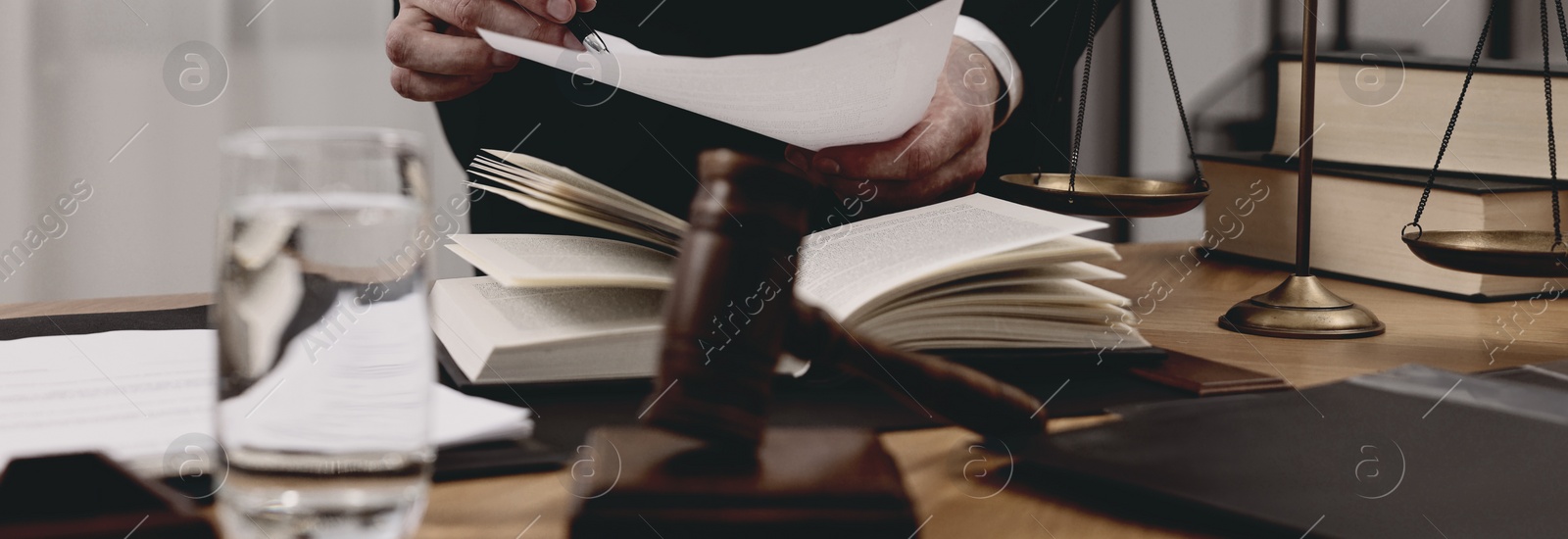 Image of Lawyer working with document at wooden table in office, closeup. Banner design