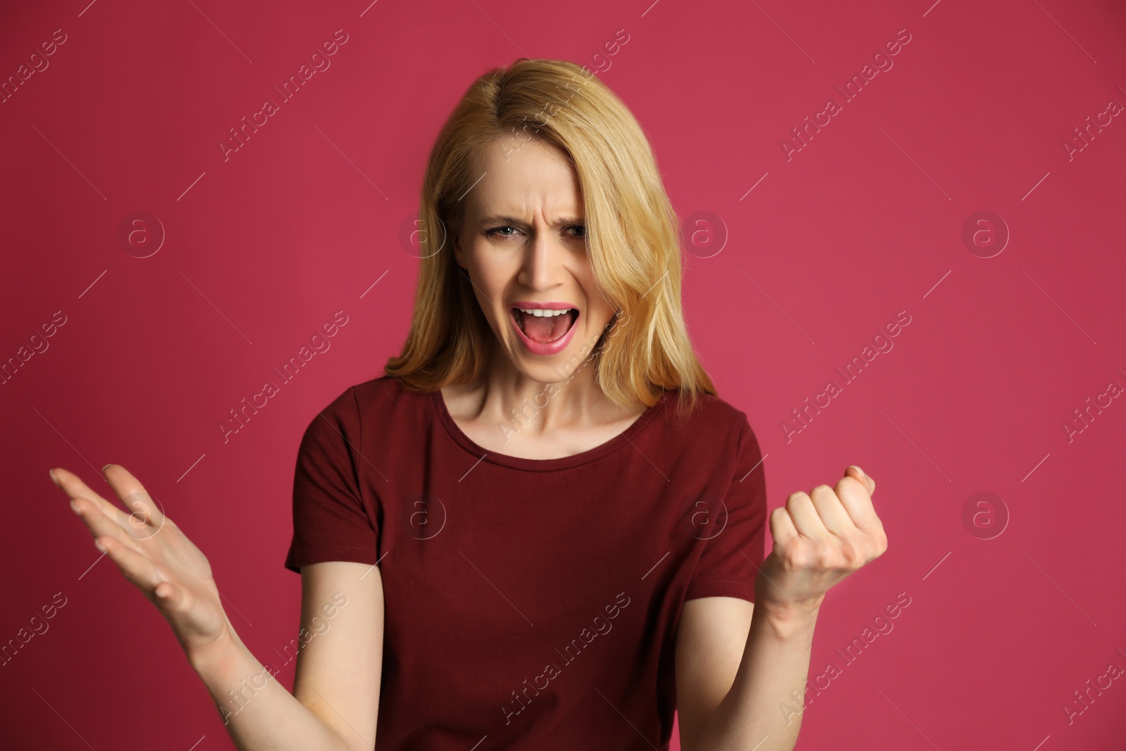 Photo of Angry young woman on pink background. Hate concept