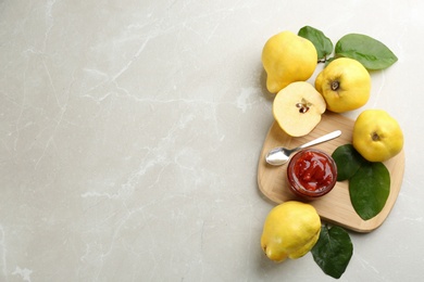 Photo of Delicious quince jam and fruits on light grey marble table, flat lay. Space for text