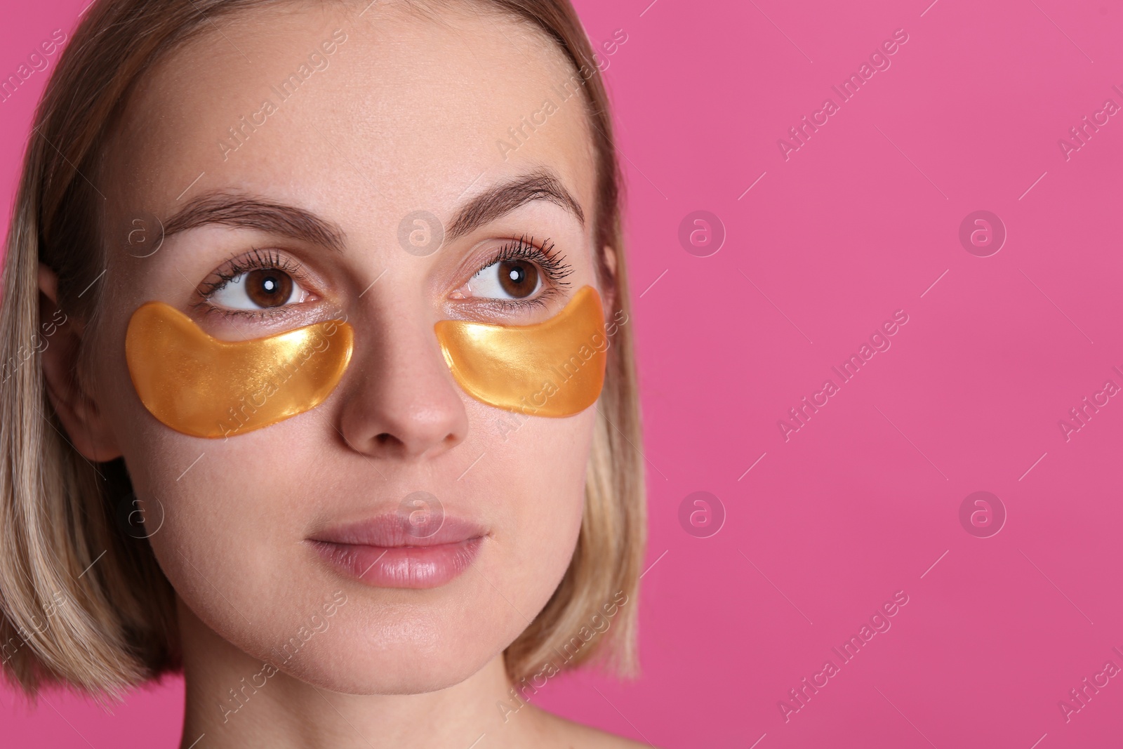 Photo of Beautiful young woman with under eye patches on pink background. Space for text