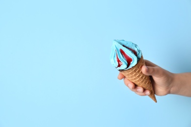 Photo of Woman holding waffle cone with delicious ice cream on color background. Space for text