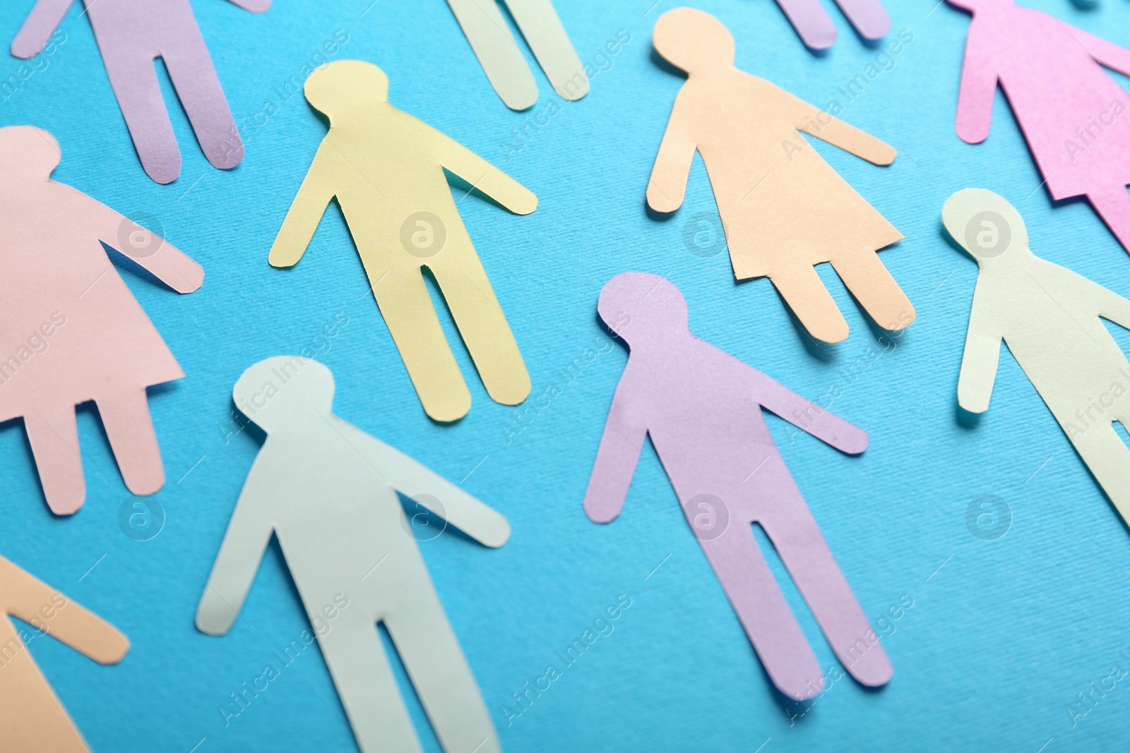 Photo of Many different paper human figures on light blue background. Diversity and inclusion concept