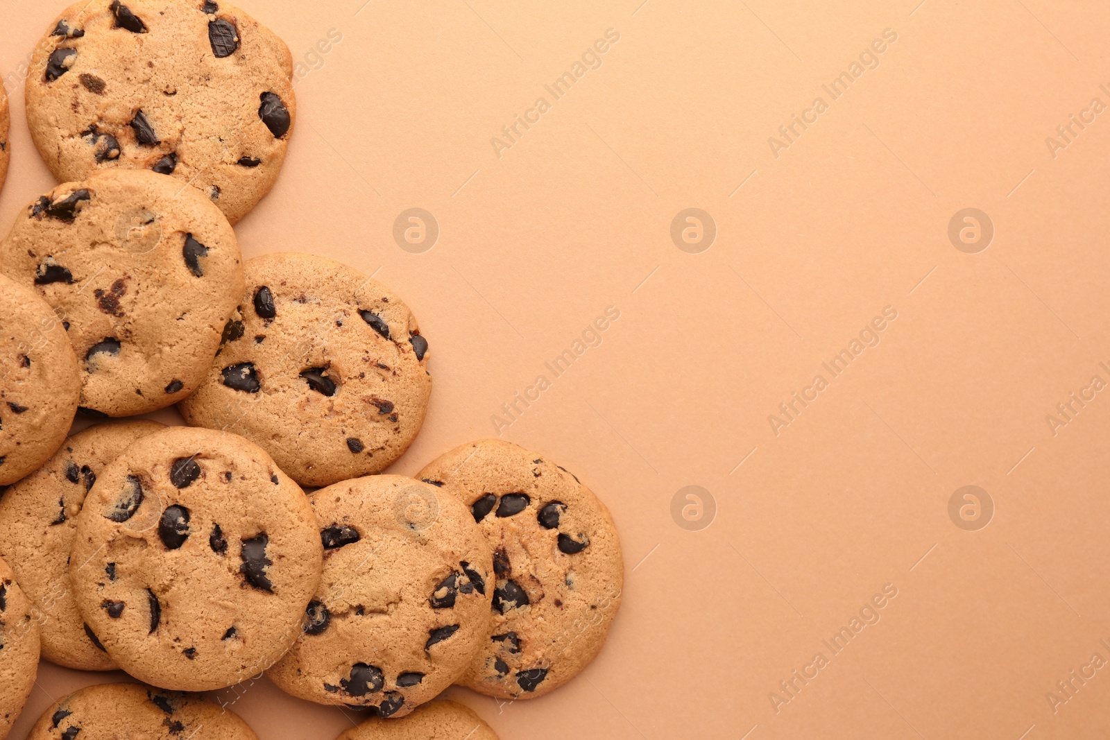 Photo of Many delicious chocolate chip cookies on beige background, flat lay. Space for text