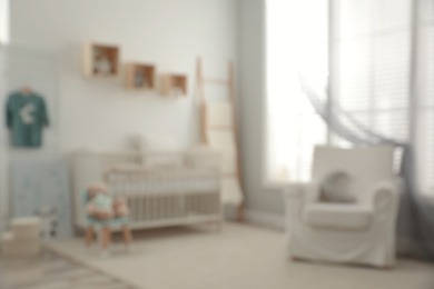 Photo of Blurred view of baby room with stylish furniture