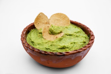 Delicious guacamole made of avocados with chips on white background, closeup