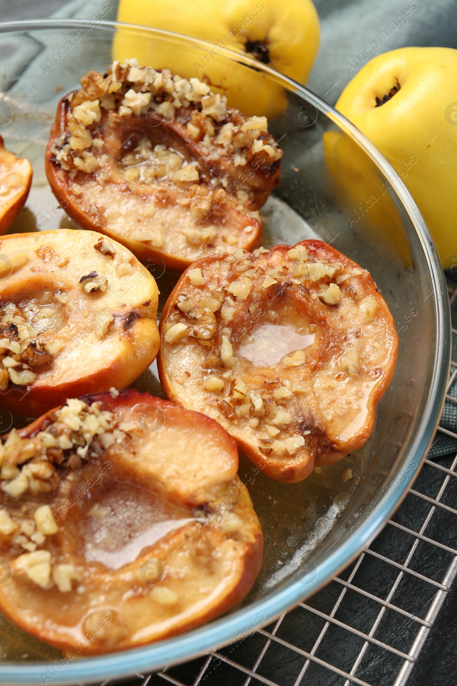 Photo of Tasty baked quinces with walnuts and honey in bowl on table, closeup