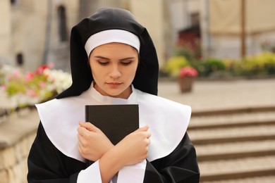 Young nun with Bible outdoors on city street