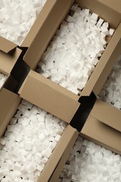 Photo of Open cardboard boxes with pieces of polystyrene foam on floor, flat lay. Packaging goods
