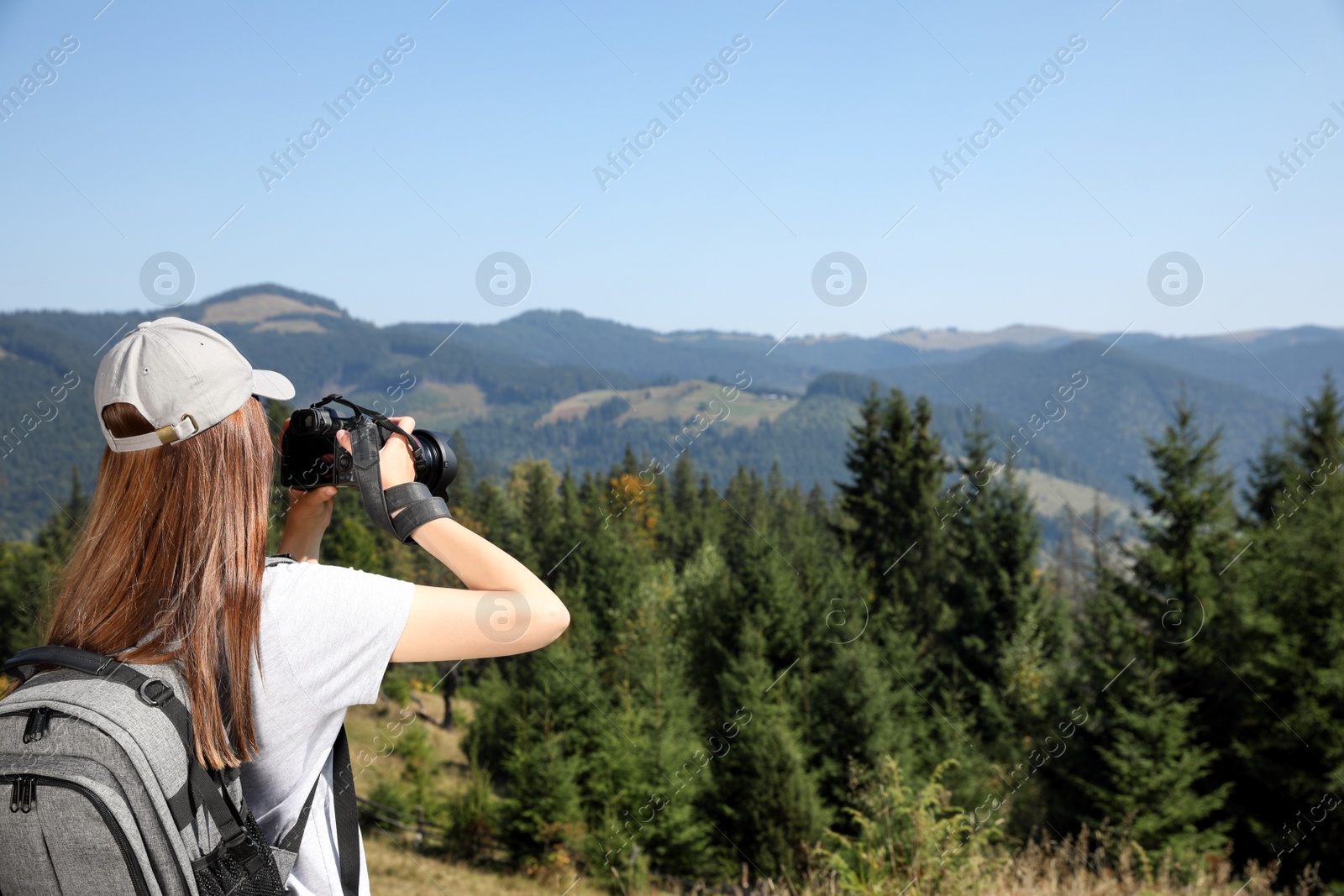 Photo of Professional photographer taking picture with modern camera in mountains. Space for text