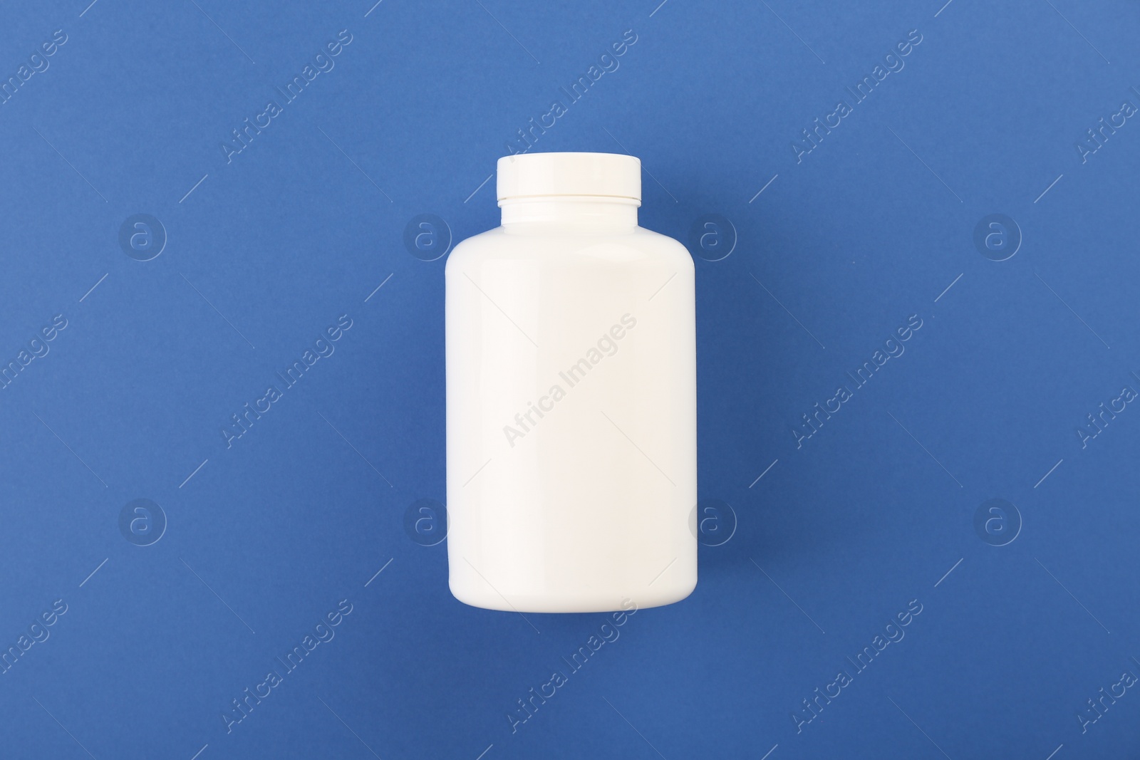 Photo of Blank white pill bottle on blue background, top view. Space for text