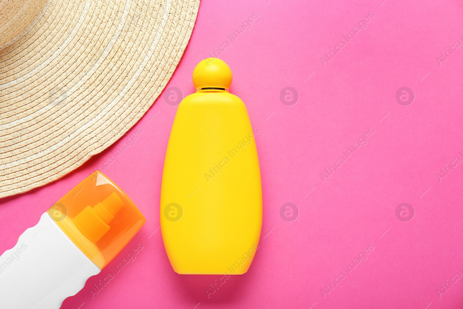 Photo of Suntan products and straw hat on pink background, flat lay. Space for text