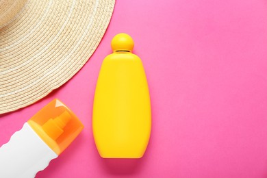 Suntan products and straw hat on pink background, flat lay. Space for text