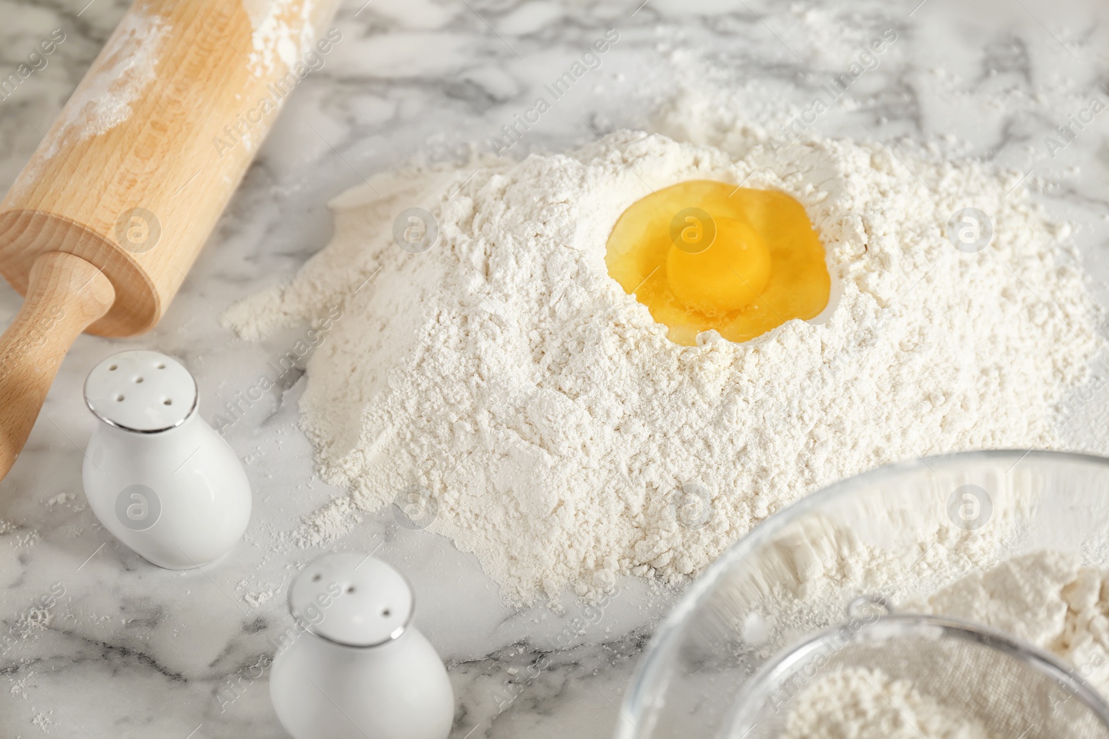 Photo of Pile of flour with egg on table in kitchen
