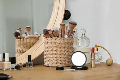 Photo of Cosmetics and brushes on dressing table in makeup room