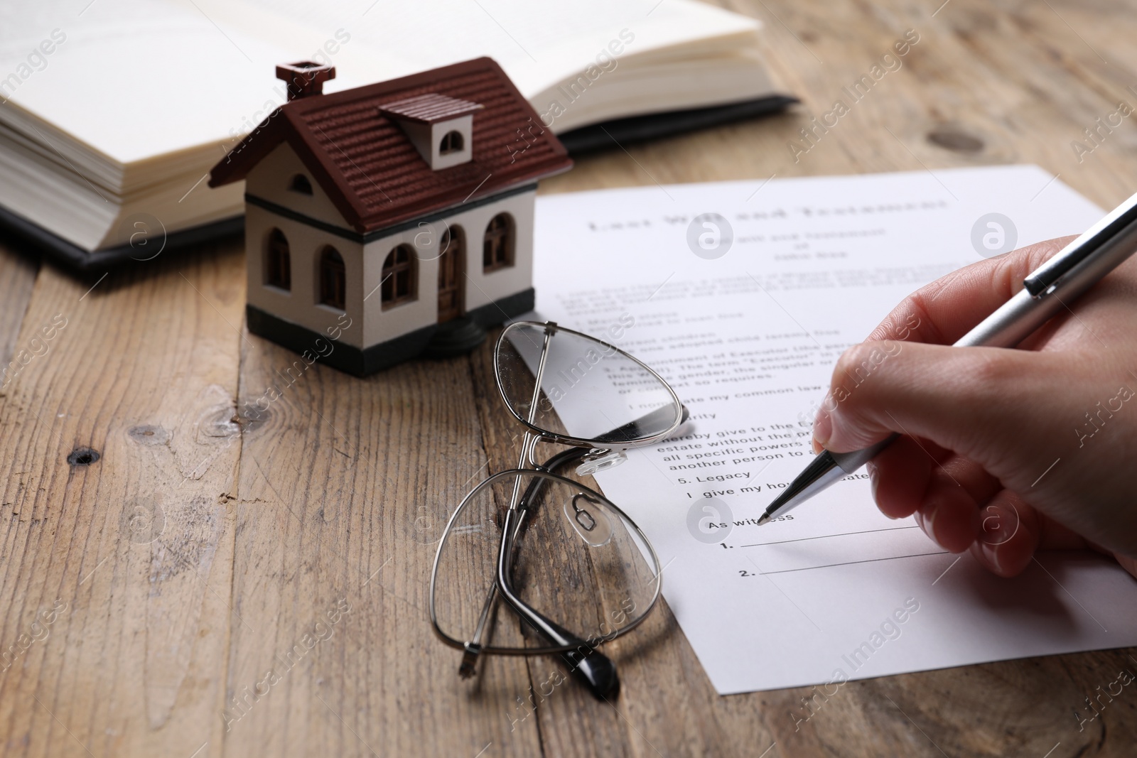 Photo of Woman signing Last Will and Testament at wooden table, closeup