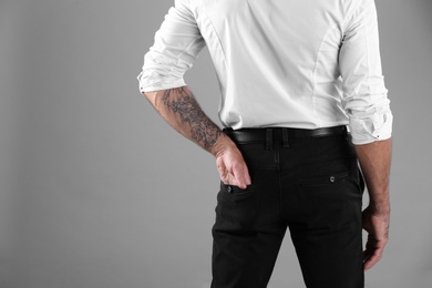 Photo of Tattooed man on grey background, closeup view. Space for text