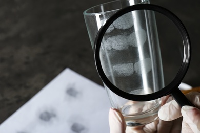 Photo of Detective exploring fingerprints with magnifying glass, closeup