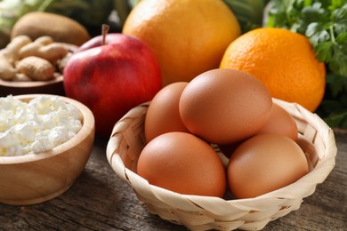 Photo of Healthy meal. Different vegetables and raw eggs on wooden table, closeup