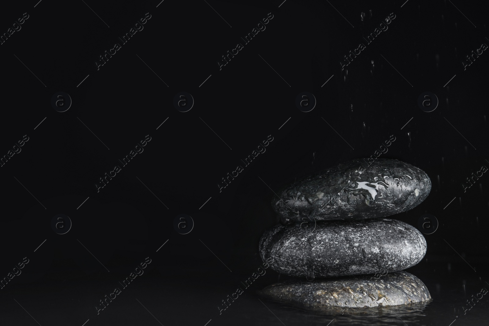 Photo of Stones in water on black background, space for text. Zen lifestyle