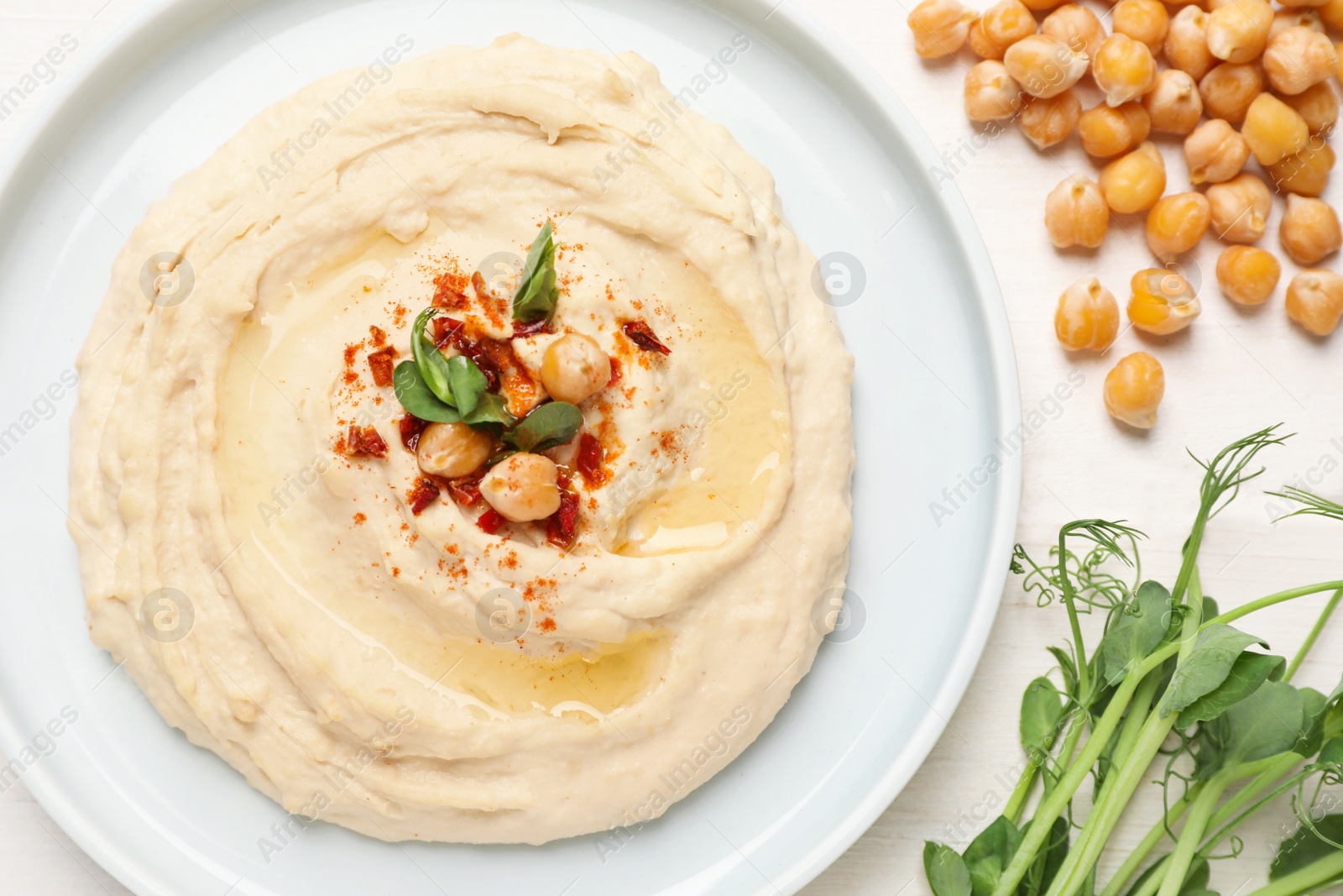 Photo of Tasty hummus with garnish served on white wooden table, flat lay