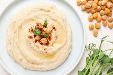 Photo of Tasty hummus with garnish served on white wooden table, flat lay