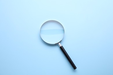 Photo of Magnifying glass on light blue background, top view