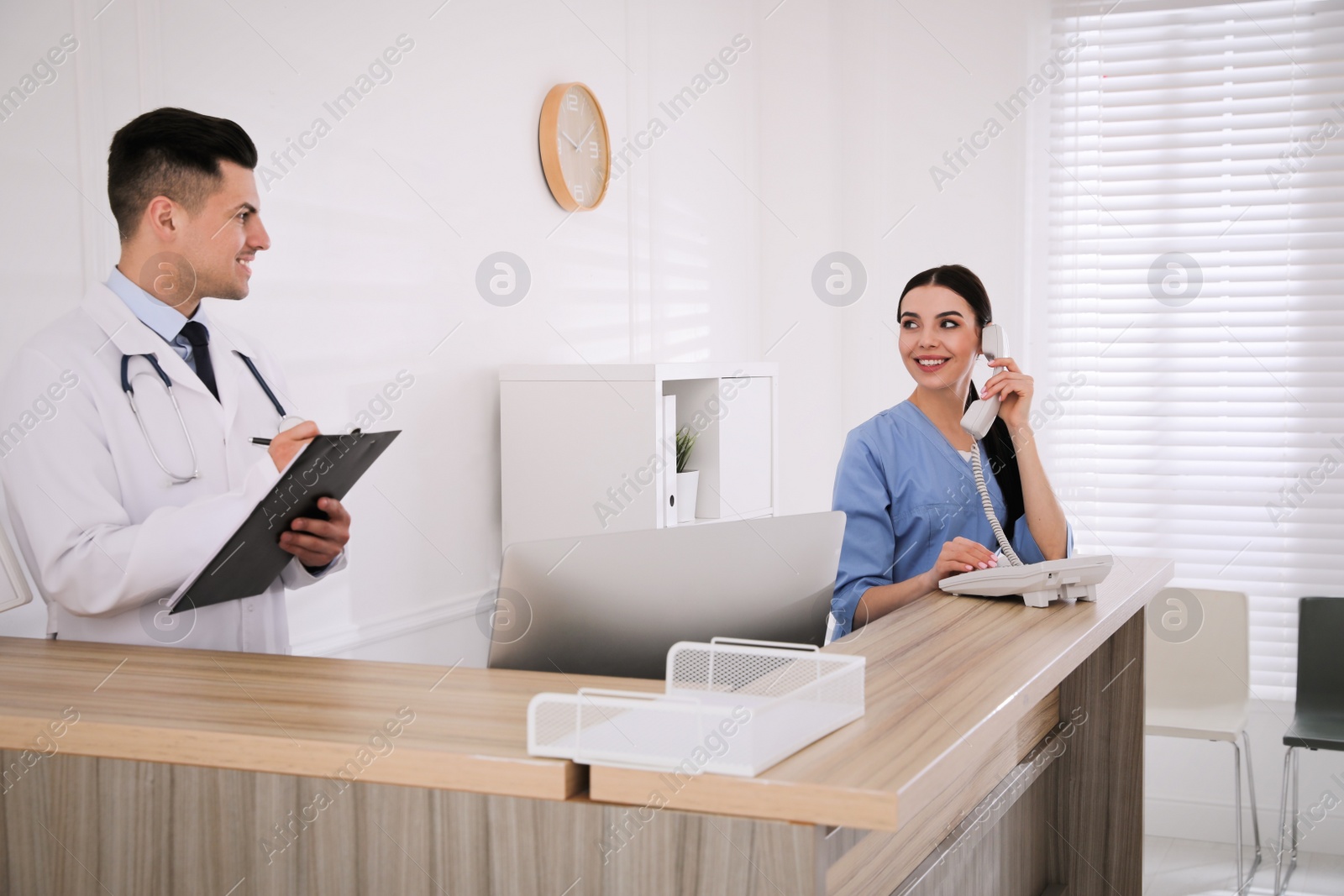 Photo of Receptionist and doctor working at countertop in hospital