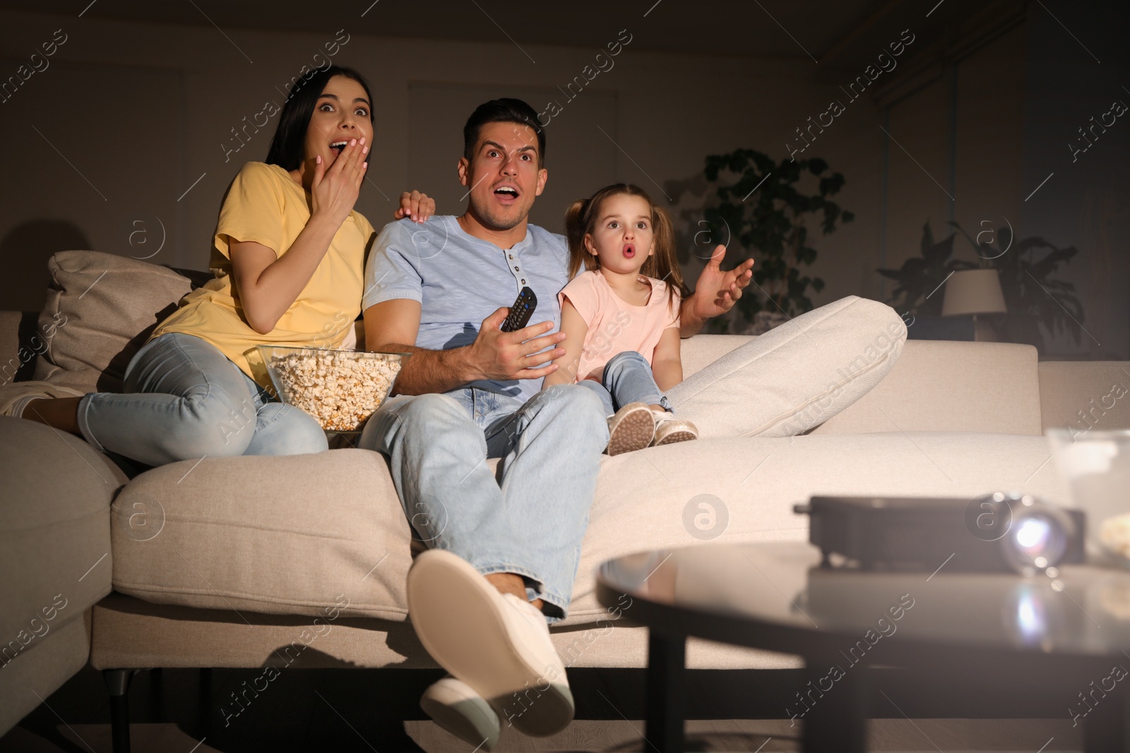 Photo of Family watching movie with popcorn on sofa at night