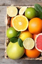 Different cut and whole citrus fruits on wooden table, top view