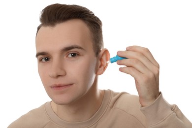 Young man using ear drops on white background