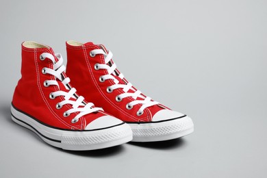 Pair of new stylish red sneakers on light grey background. Space for text