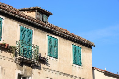 Photo of Old residential building with balcony against light blue sky