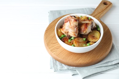 Photo of Tasty cooked rabbit with vegetables in bowl on white table, space for text