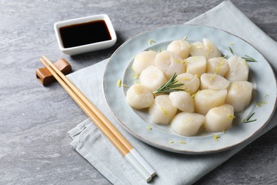 Raw scallops with lemon zest and rosemary on grey marble table, closeup