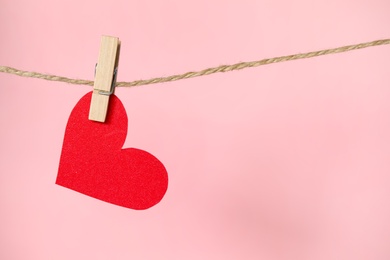 Photo of Decorative heart hanging on twine against pink background, space for text. Valentine's Day