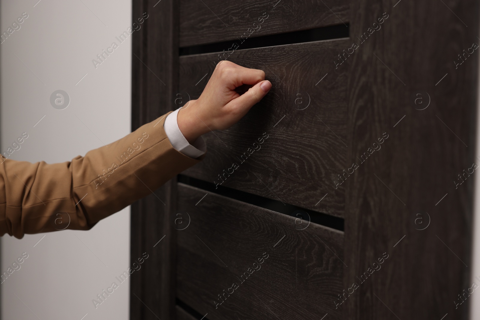 Photo of Collector knocking on door indoors, closeup view