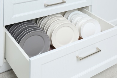 Photo of Open drawer with clean plates indoors. Order in kitchen