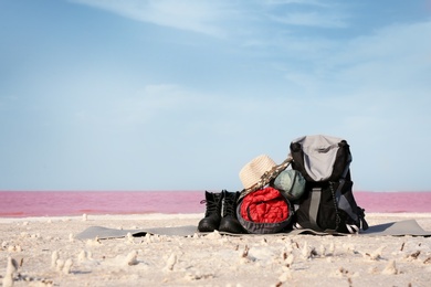 Set of camping equipment with sleeping bag on coast of pink lake