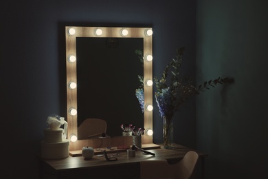 Photo of Table with beautiful mirror and cosmetics in modern makeup room