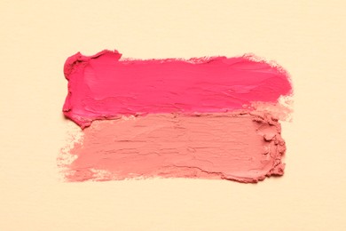 Photo of Smears of beautiful lipsticks on beige background, top view
